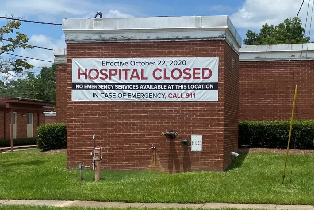 Image of a hospital with a sgn that states "Hospital closed - no emergency services Available at this location. in case of emergency call 911. effective October 22, 2020."